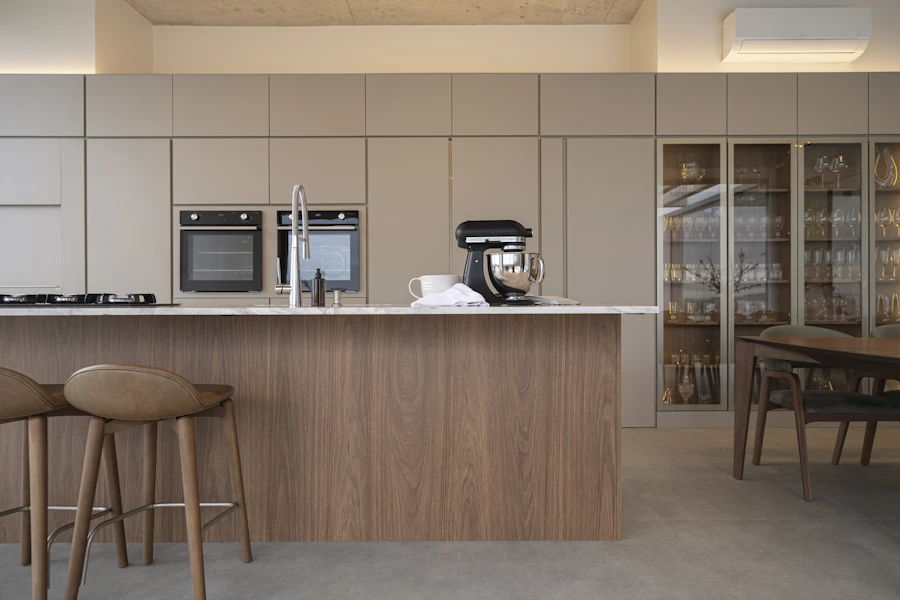 Kitchen with putty-coloured cabinetry, a long oak island and wooden stools