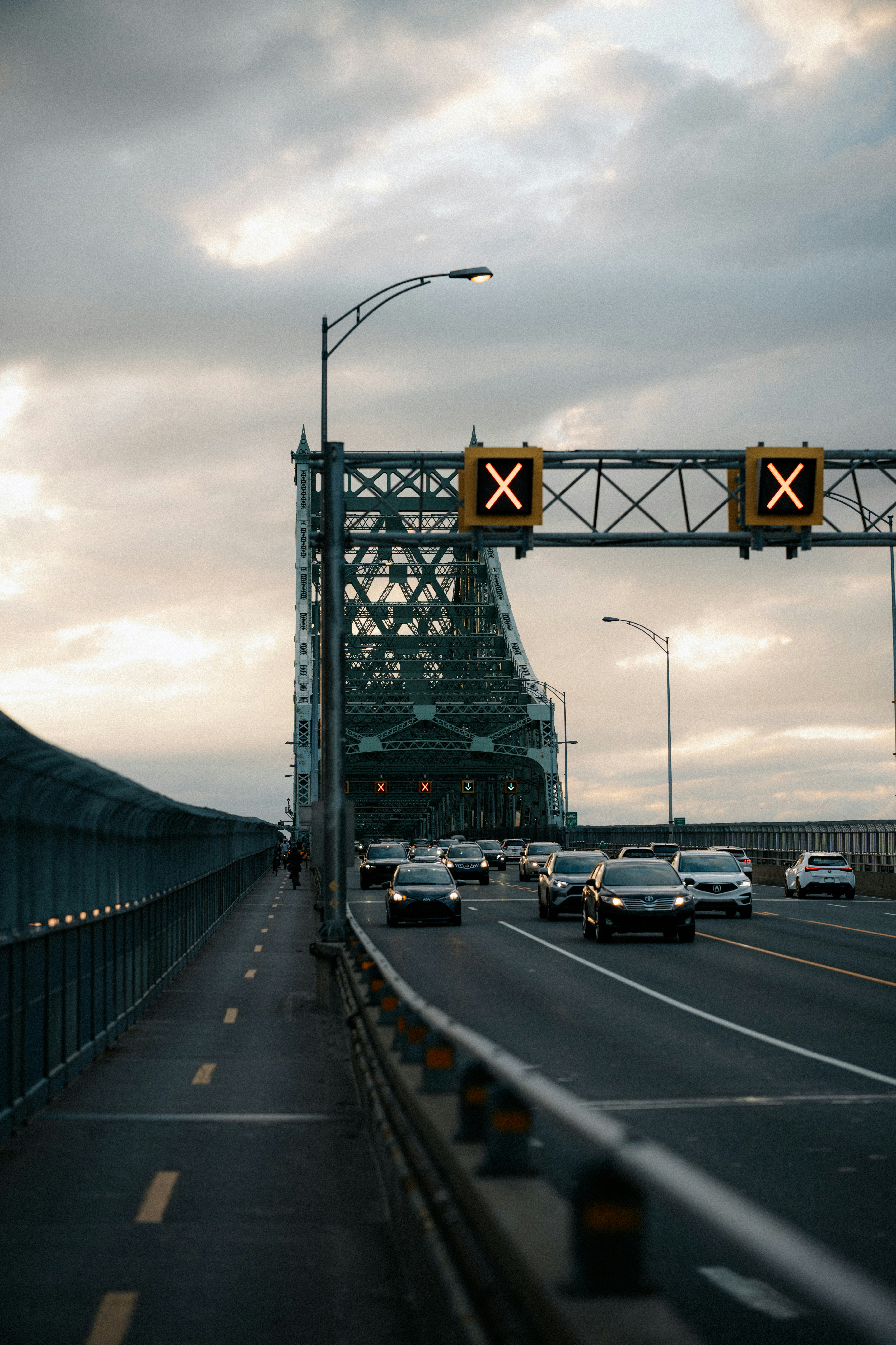 Cars driving on a bridge under cloudy sky.