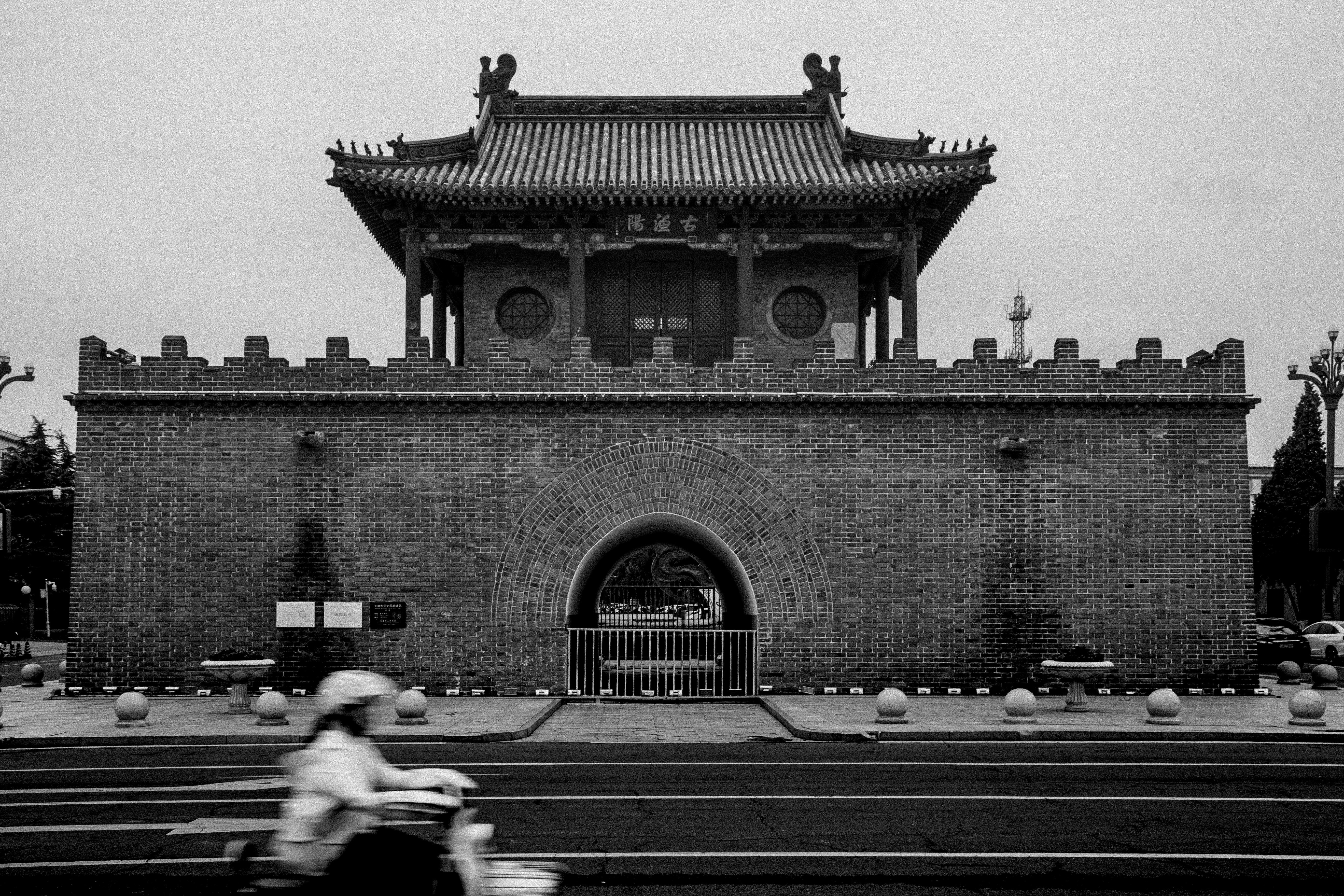 Historic brick gatehouse with a person on a scooter.
