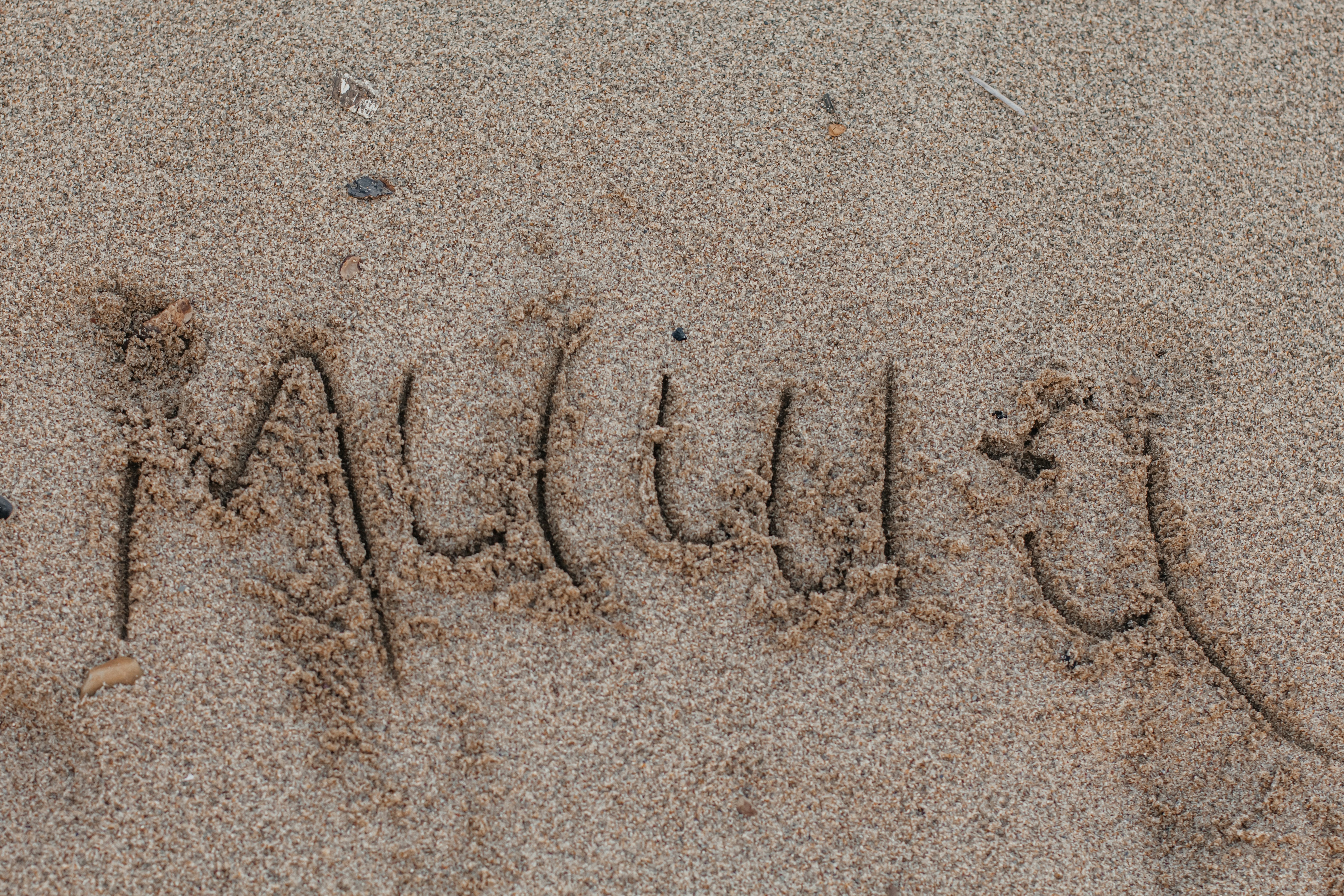 젖은 모래에 쓰여진 "알리우아"라는 단어.