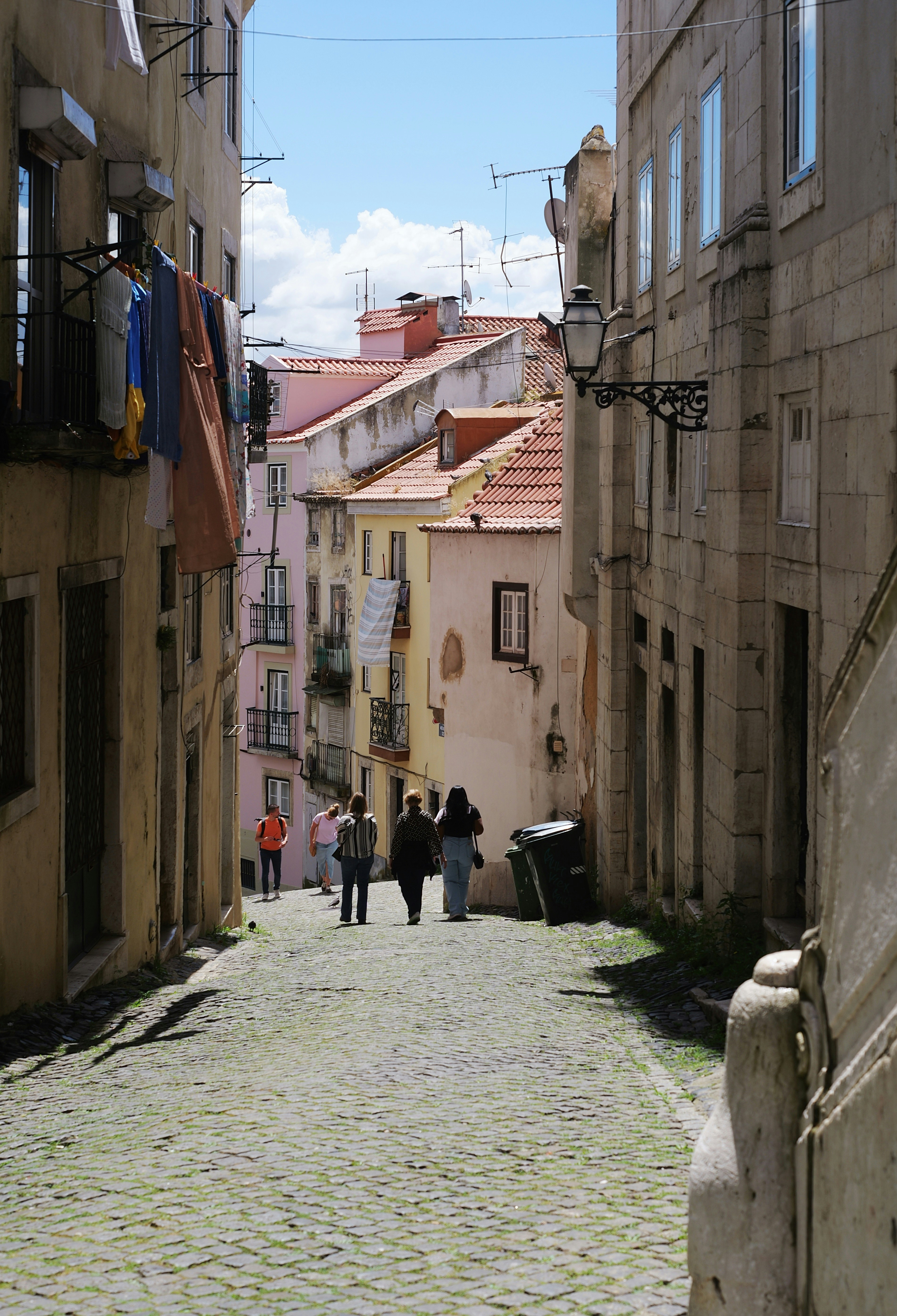 People walking up a cobblestone street lined with buildings
