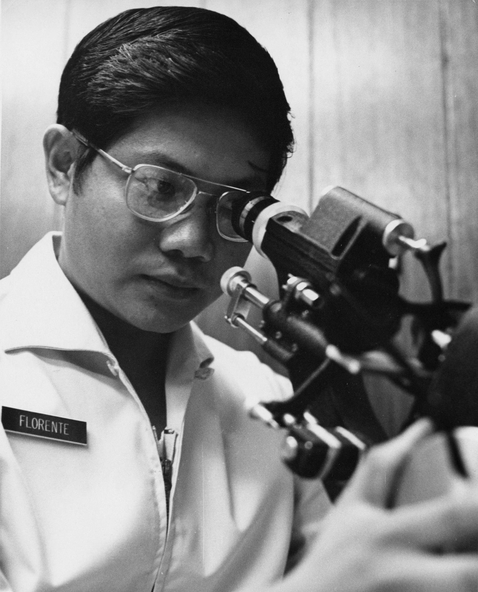 Man wearing glasses looks through a telescope
