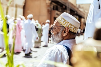 Elderly man in traditional white cap and clothing.