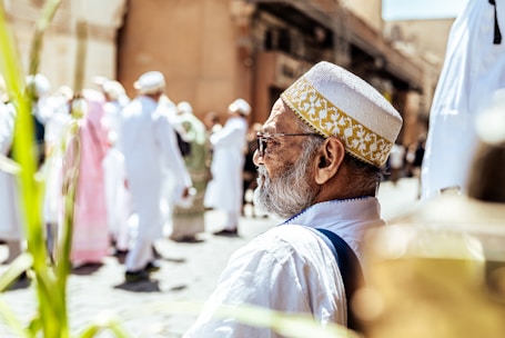 Elderly man in traditional white cap and clothing.