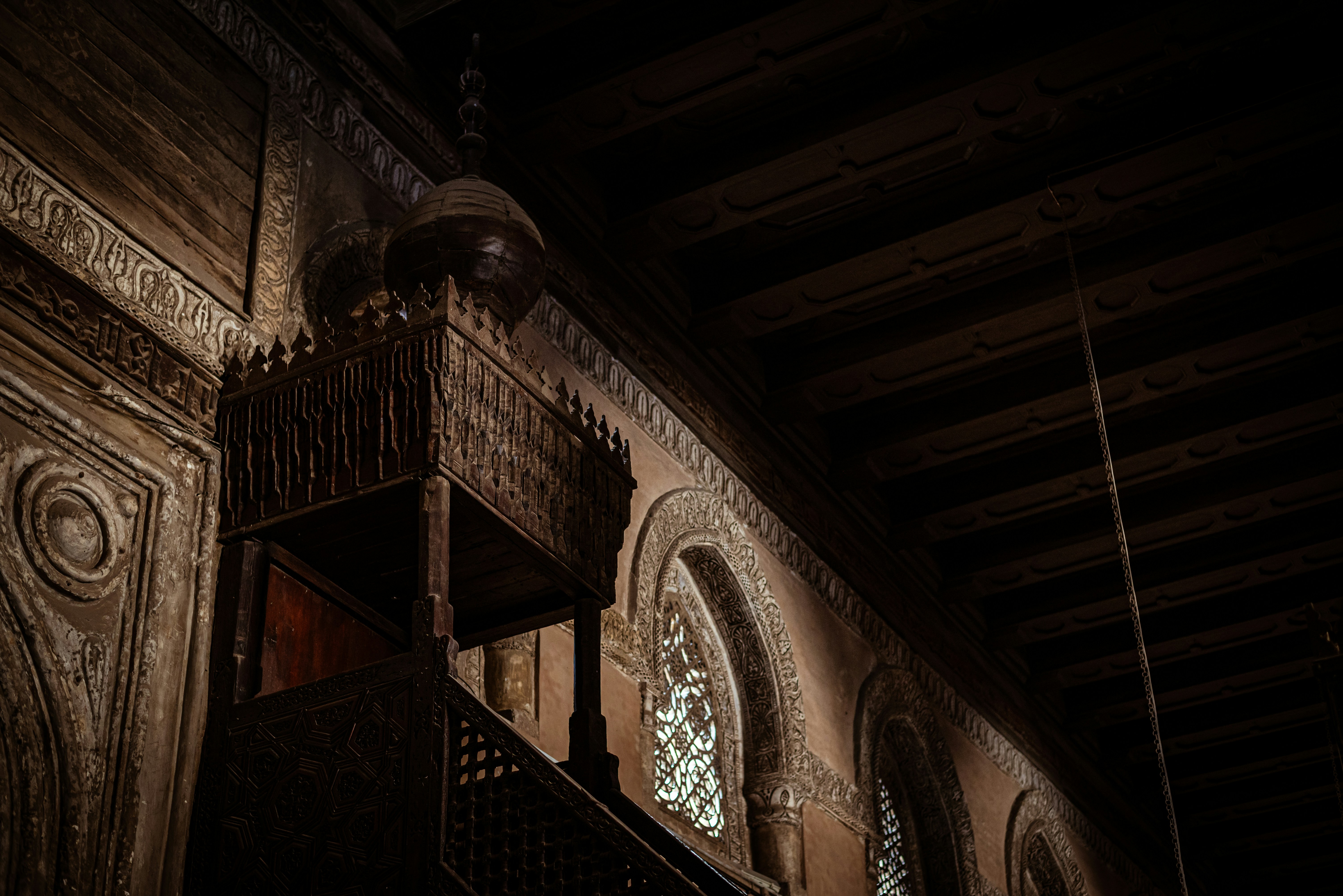 Ornate wooden minbar with arched windows in dim light