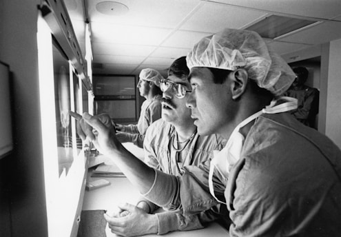 Surgeons examining x-rays in a dimly lit room.