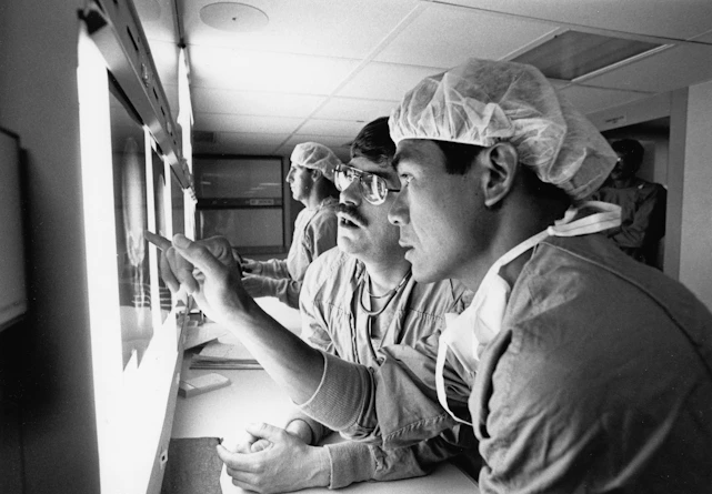 Surgeons examining x-rays in a dimly lit room.