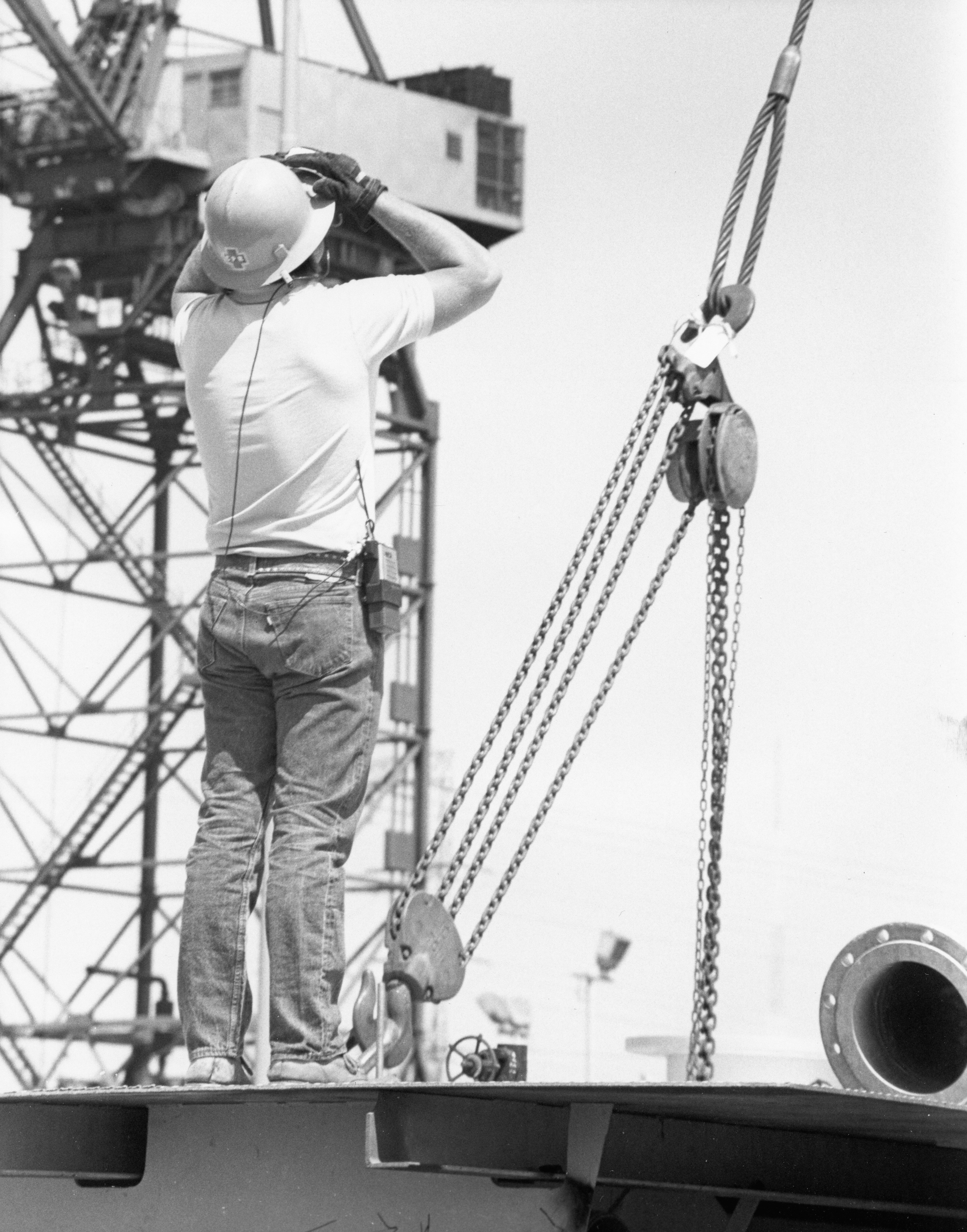Worker in hard hat on platform near crane