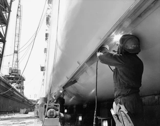 Welder working on a large ship hull in dry dock.