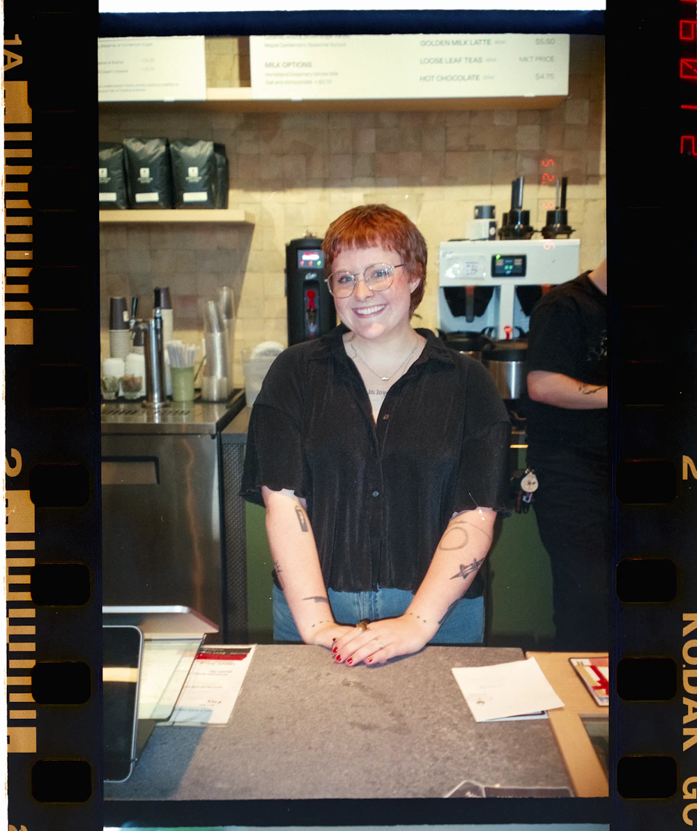 A friendly cafe worker smiling behind the counter