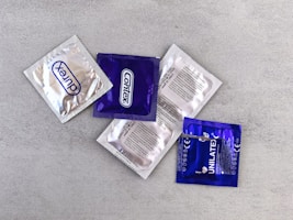 Several individually wrapped condoms on a gray surface.