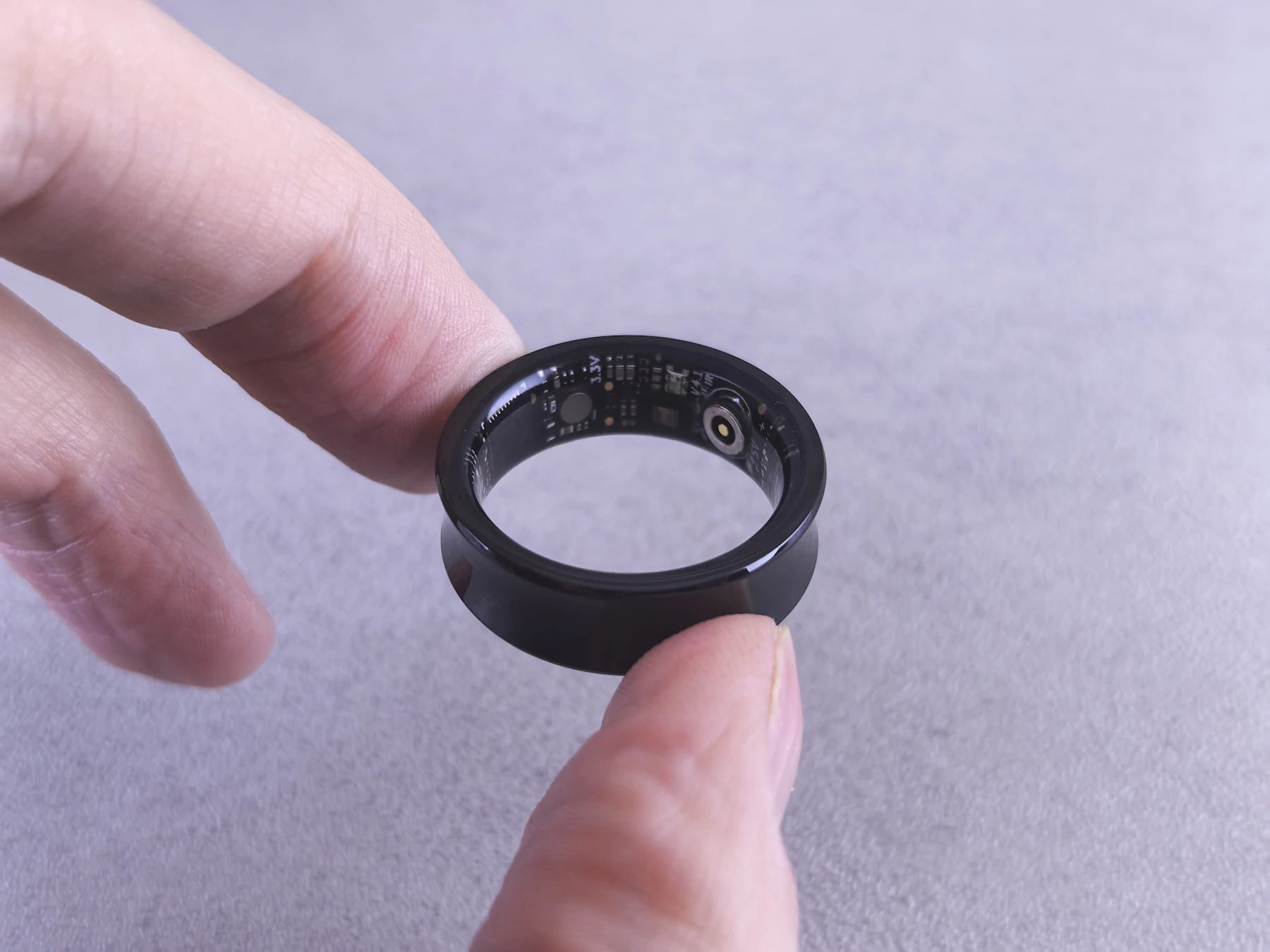 A black smart ring held between two fingers