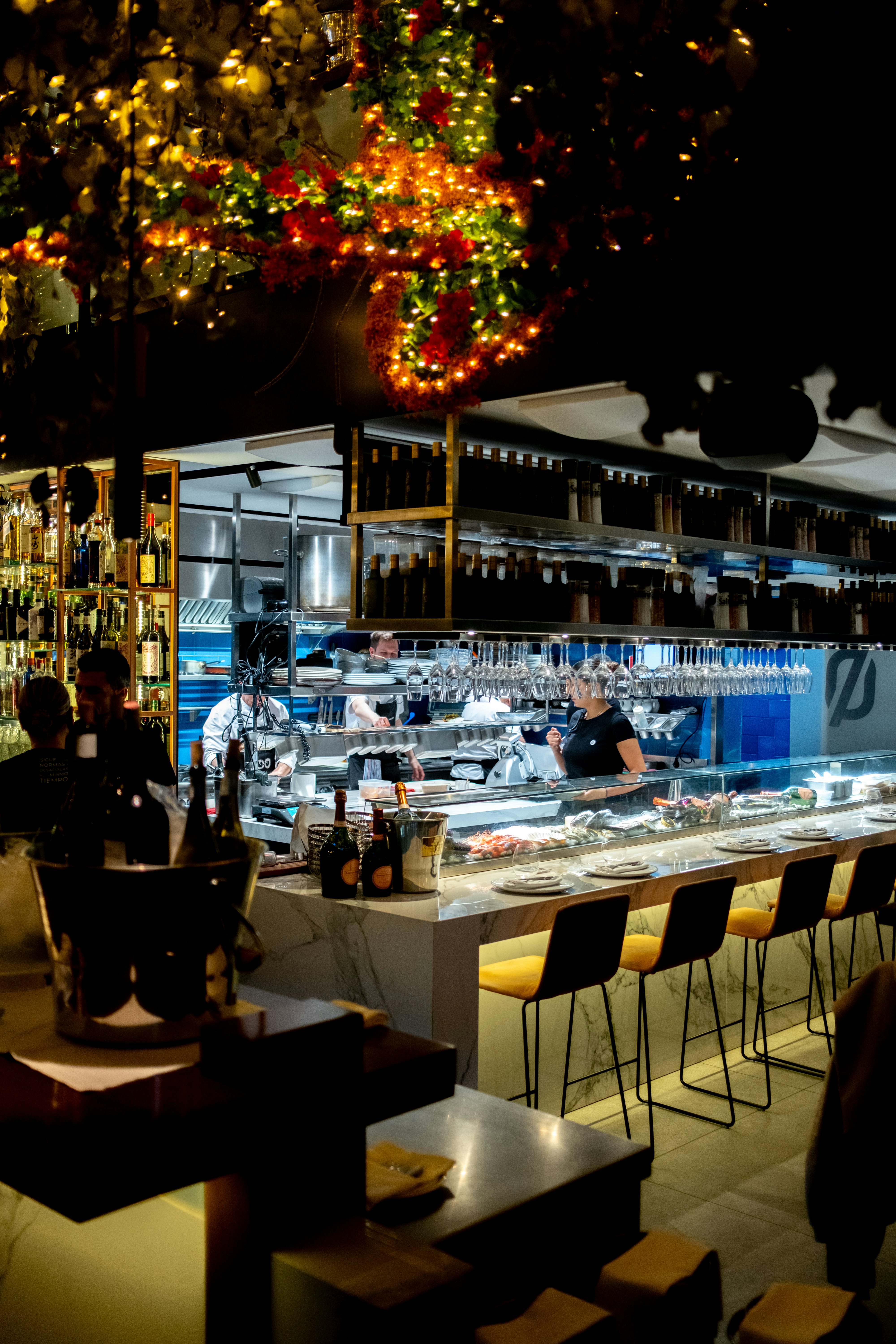 Busy restaurant bar area with chefs working in background.