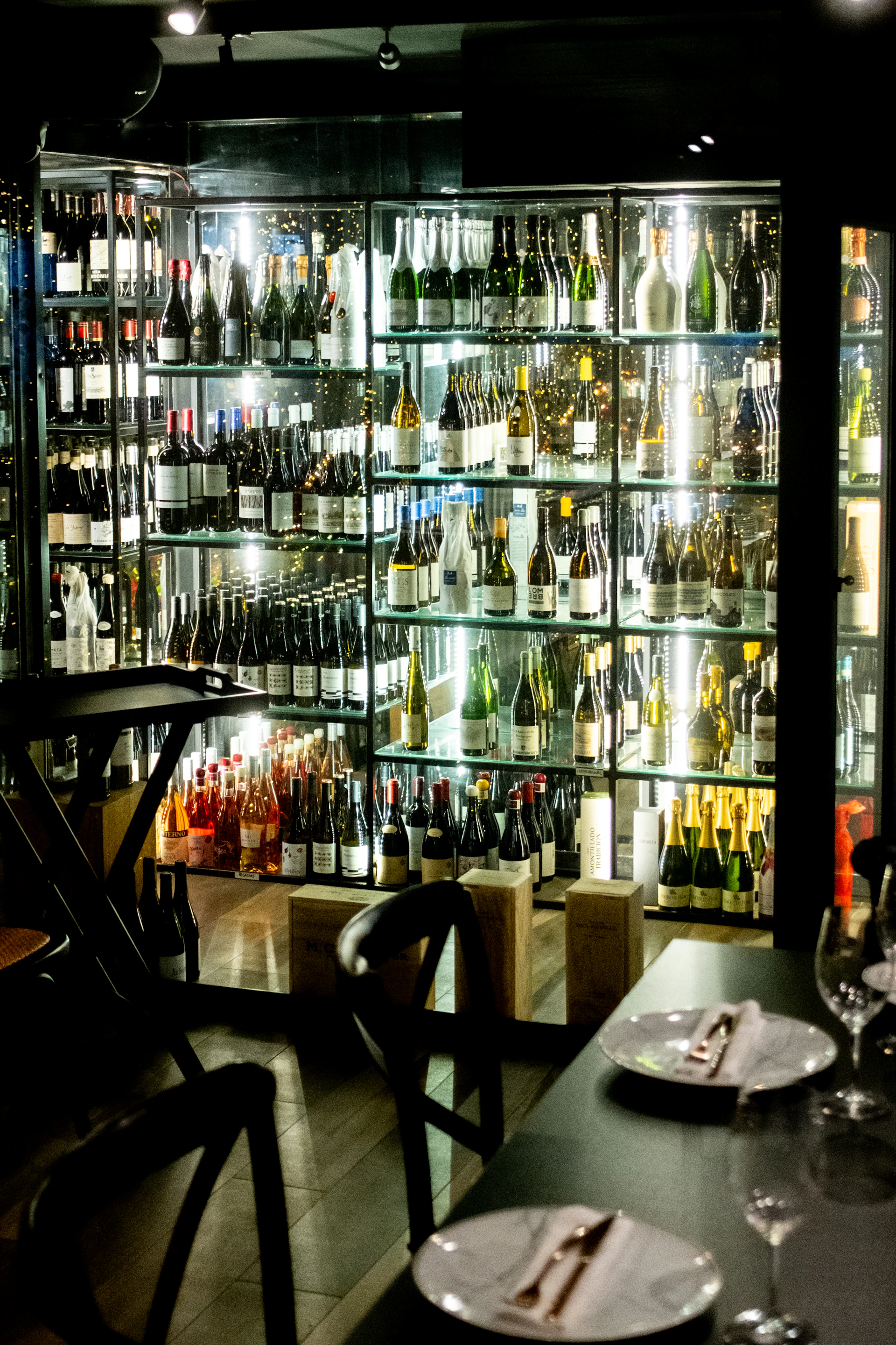 Wall of wine bottles displayed in a dimly lit establishment.