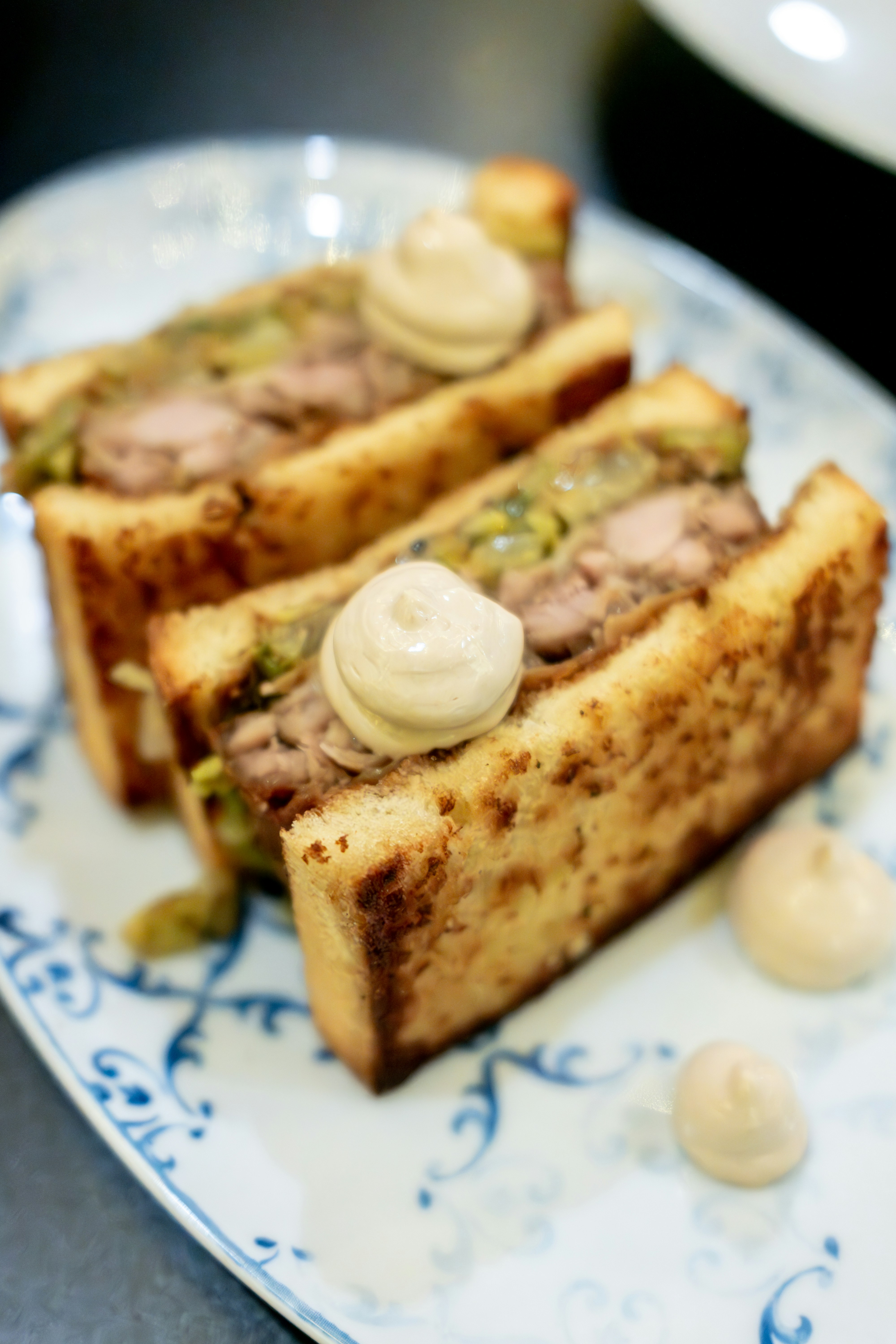 Three gourmet sandwiches with creamy topping on plate