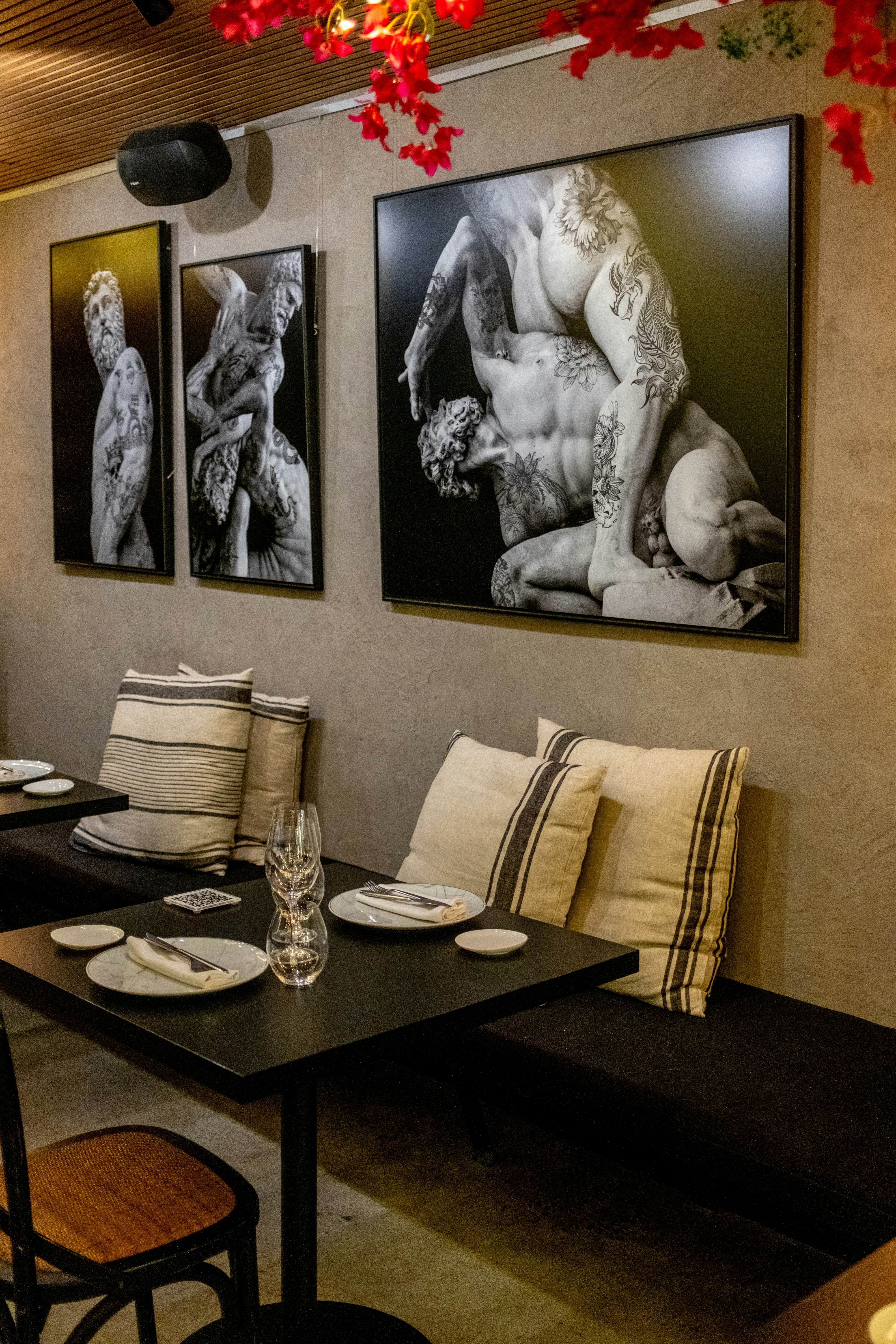 Three framed artworks of muscular figures hang on wall.