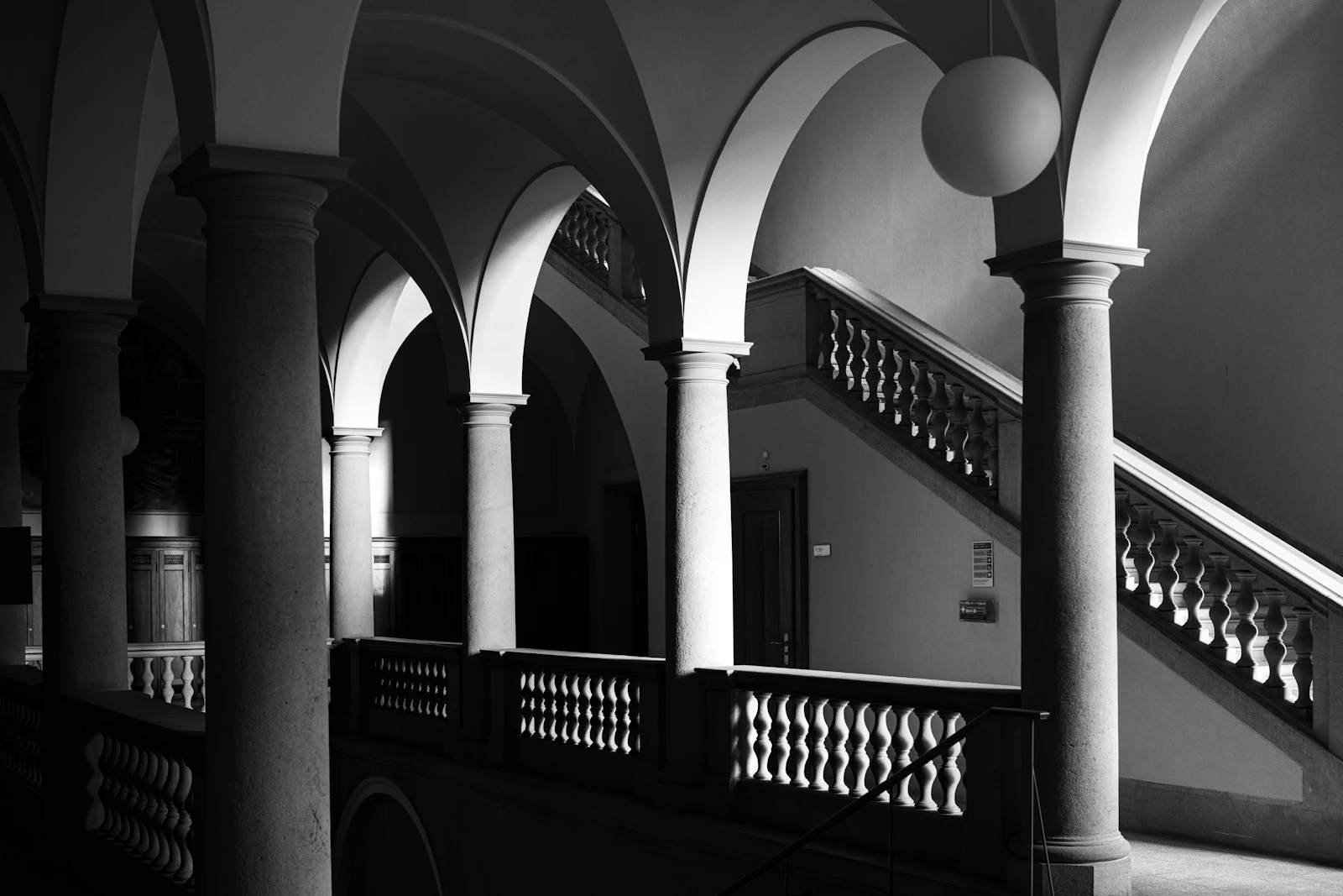 A grand staircase beneath stone arches, in black and white