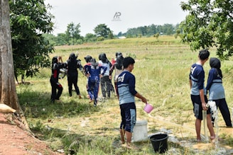 Group of young people gathered outdoors by water.