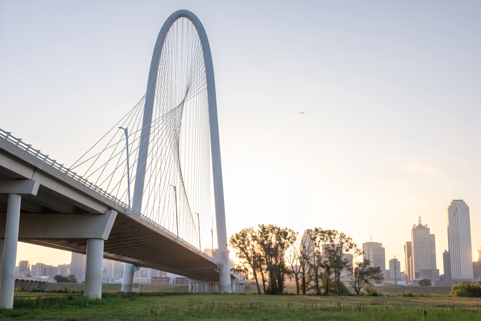 The Margaret Hunt Hill Bridge at sunrise over the Trinity River, Dallas skyline behind