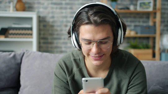 Joven usando auriculares y usando un smartphone tomando terápia psicológica