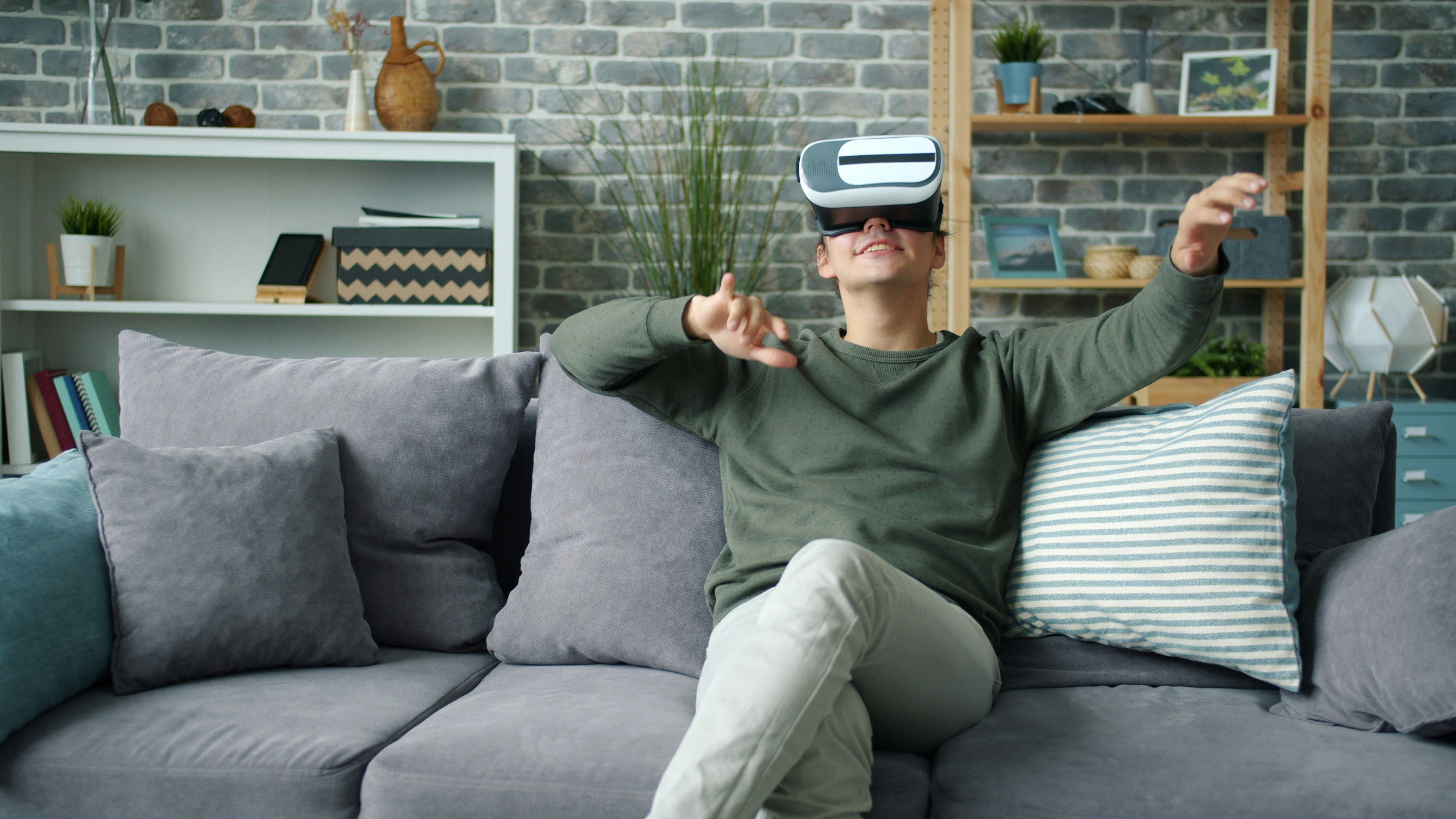 Man using VR headset on couch, gesturing