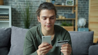Young man using smartphone and credit card for online shopping.