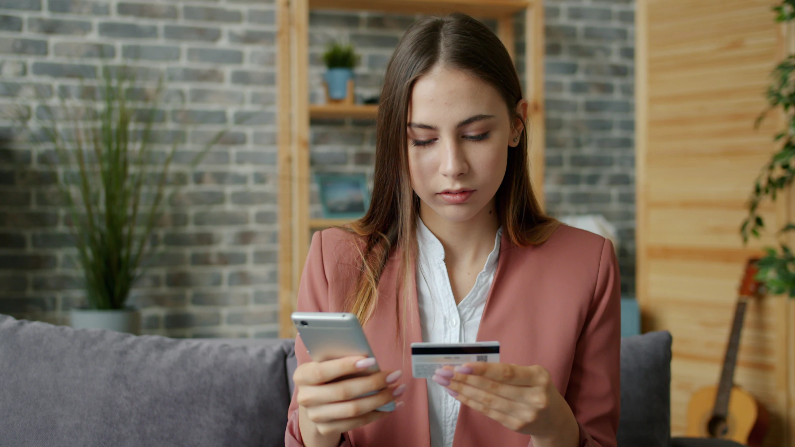Молода жінка користується смартфоном і банківською карткою