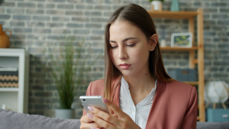 Young woman looking at her smartphone screen browsing a salon booking website