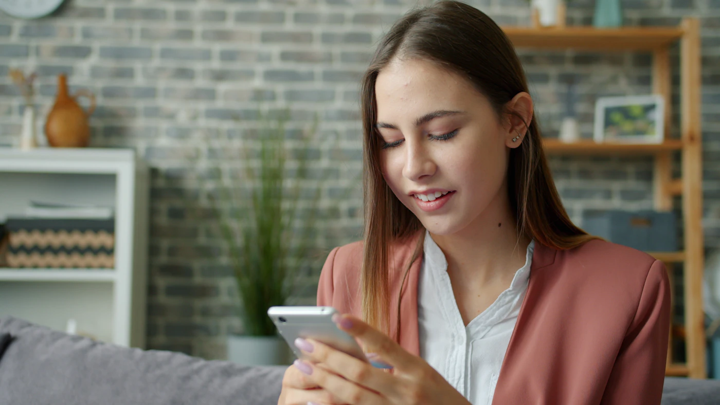 Woman sitting alone while looking at social media on her phone after a breakup