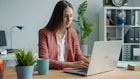 Woman working on laptop at office desk.