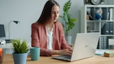 Woman working on laptop at office desk.