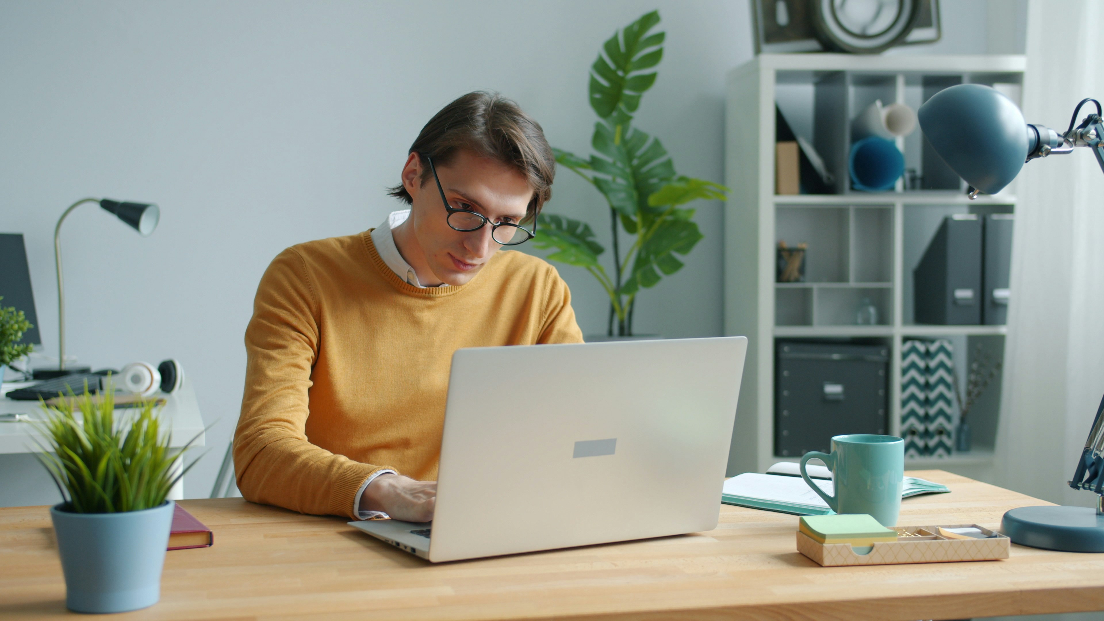A man wearing glasses analyzes graphs on a computer screen displaying an AI management tool.