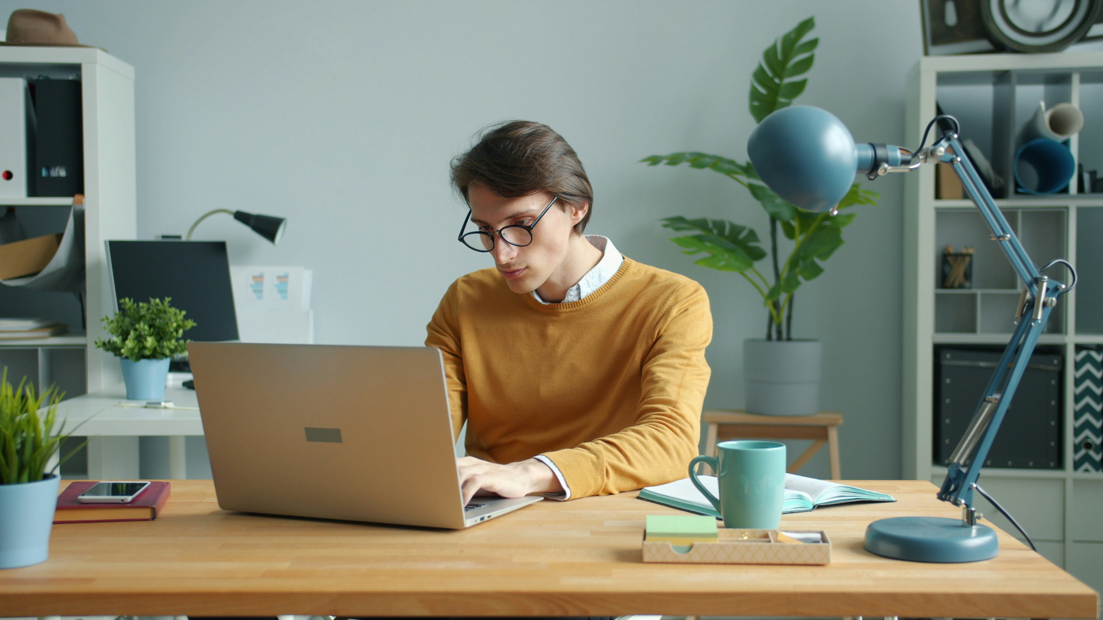 Tired young businessman working with laptop feeling exhausted