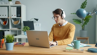 Man wearing headphones working on laptop at desk
