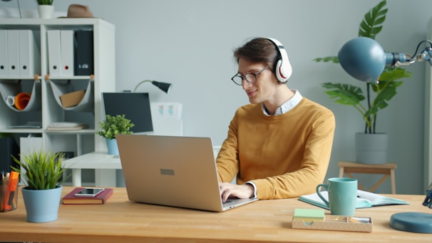 Man wearing headphones working on laptop at desk