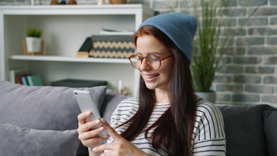 Young woman wearing a beanie and glasses using phone.