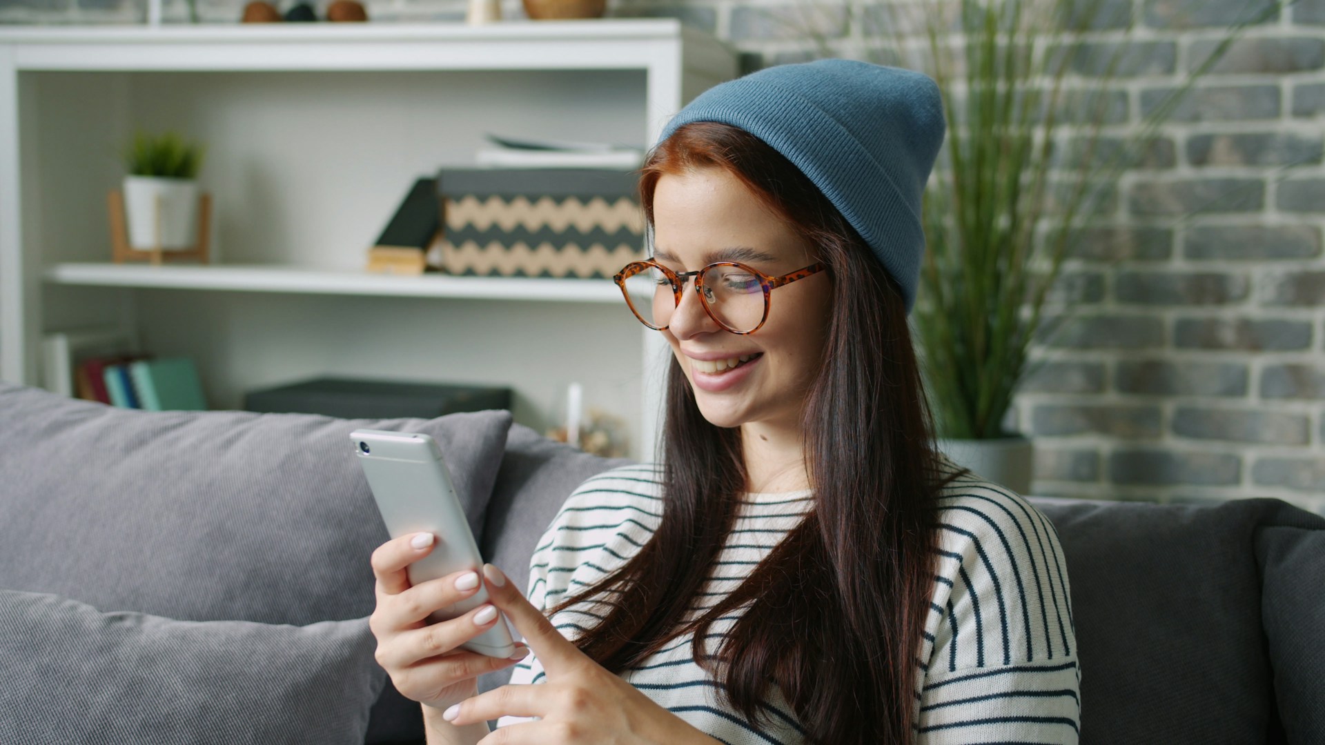 Young woman wearing a beanie and glasses using phone.