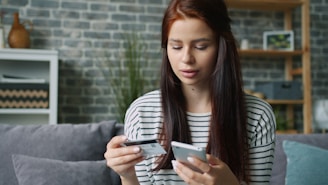 Woman holding credit card and smartphone for online shopping.