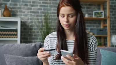 Woman holding credit card and smartphone for online shopping.