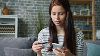 Woman holding credit card and smartphone for online shopping.
