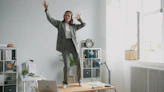 Woman in suit dancing on desk with headphones