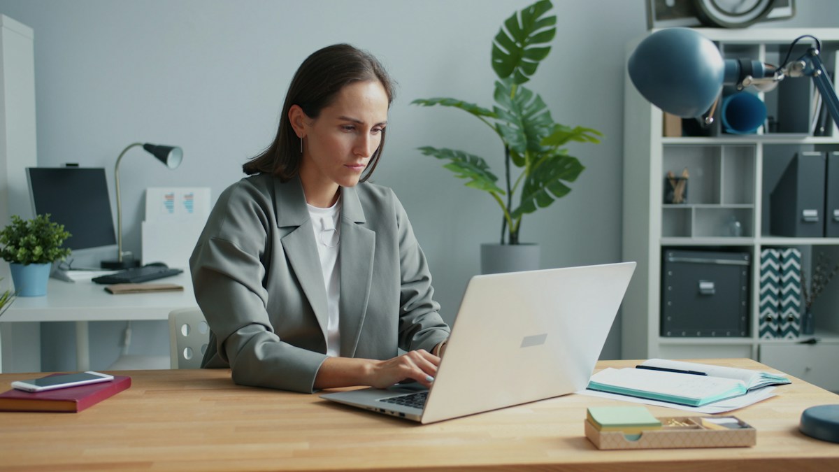 Woman typing on a laptop at a desk, illustrating school email newsletter creation for effective parent communication.