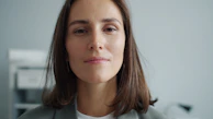 A woman with brown hair wearing a gray blazer