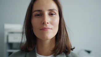 A woman with brown hair wearing a gray blazer