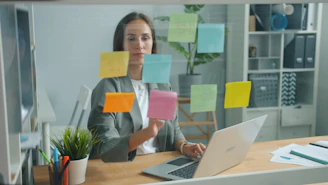 Woman placing sticky notes on glass board