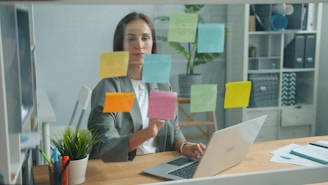 Woman placing sticky notes on glass board