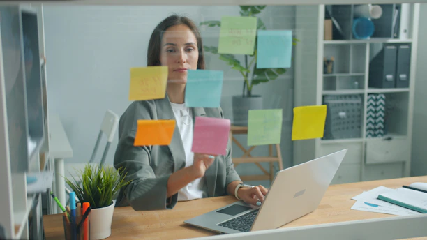 Woman placing sticky notes on glass board