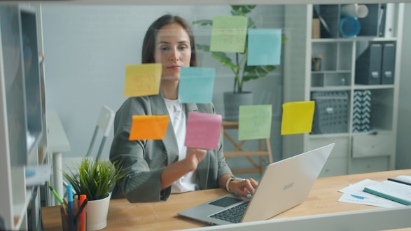 Woman placing sticky notes on glass board