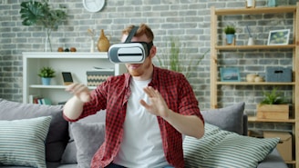Man wearing virtual reality headset playing game at home