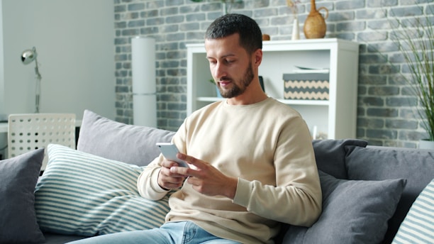 Man sitting on sofa using smartphone